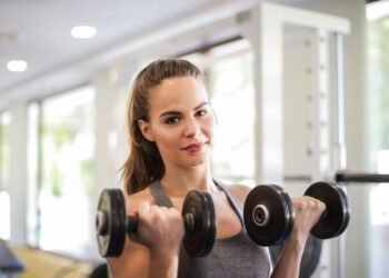 Woman doing bicep curls with adjustable dumbbells at home gym – budget fitness equipment India